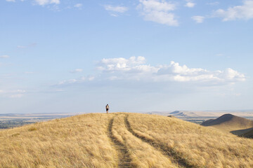 Obraz premium a lone tourist stands on a mountain path, looking into the distance Karamuruntau mountain range landscape