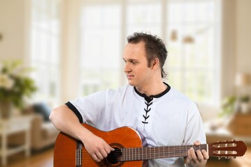 Young happy man play guitar at home.