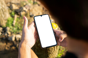 Mockup image of a man holding a smartphone with a blank screen for mobile app design or text advertisement © M_Yunus