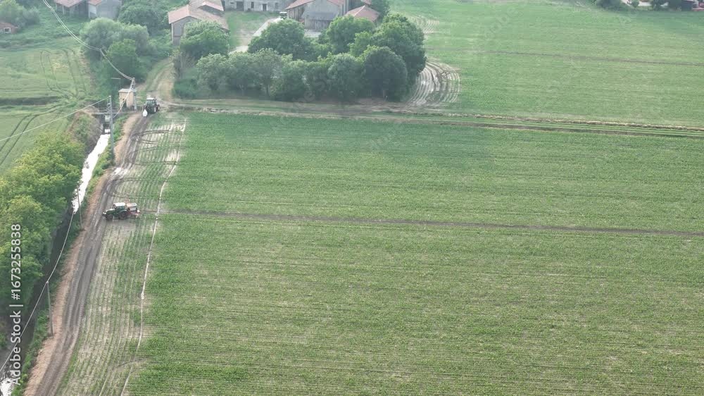 Poster aerial view of a tractor spraying a large green agricultural field with neat rows of soybean crops u