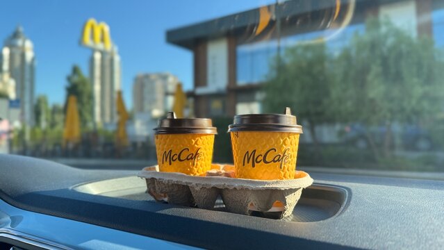 Ukraine, Kyiv - August 29, 2025: Yellow cups of McCafe coffee on the dashboard of a car bought at McDonald`s restaurant.