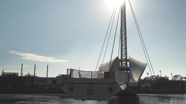 Modern footbridge opening at riverside cityscape with sunlight and blue sky