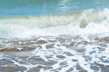 Blue sea and large waves and foam. Storm Wave splashing over pebbles at sea. Rolling ocean waves. Summer paradise beach background. Powerful sea waves