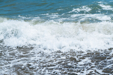 Blue sea and large waves and foam. Storm Wave splashing over pebbles at sea. Rolling ocean waves....