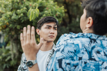 A young Southeast Asian man fearlessly confronts a larger peer, staring him down with cold...