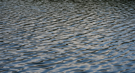 Gentle ripples on dark blue water surface creating calming, natural abstract patterns