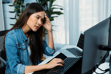 Young Asian IT developer analyzing online software development information on pc screens and...