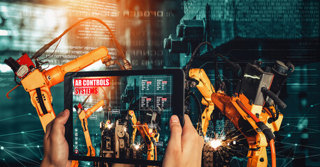 Engineer controls robotic arms by augmented reality industry technology application software. Smart robot machine in future factory working in concept of Industry 4.0 or 4th industrial revolution.