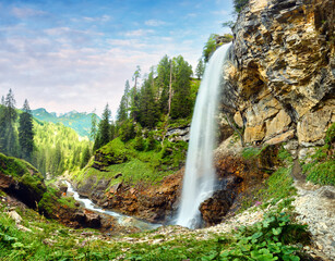 Johannes Waterfall cascades beautifully down rocky cliffs in Obertauern. Towering trees surround the area, creating a serene environment perfect for nature lovers and hikers seeking adventure.