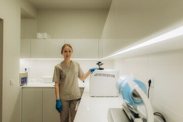 Doctor wearing blue gloves operating autoclave sterilizer in modern clinic