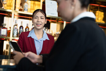 Attractive saleswoman, cashier serving customers at a retail store counter or bar restaurant counter.