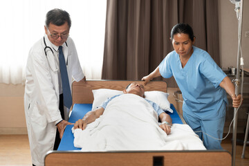 Fototapeta premium Doctor and nurse moving man lying in hospital bed resting with eyes closed at hospital 