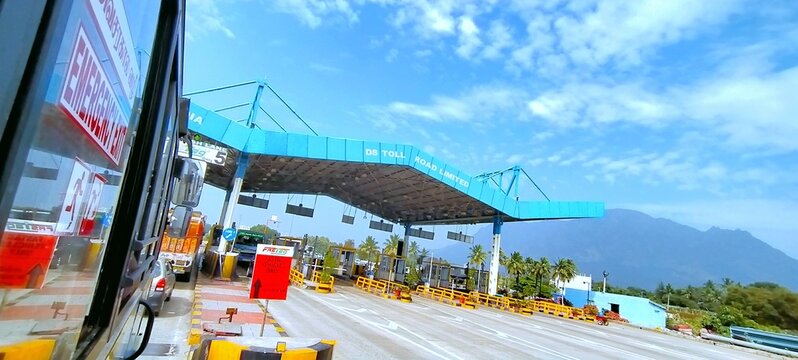 Kodaikanal Road, Tamil Nadu, India - December 27, 2020: Vehicles pass through the DS Toll Road Limited plaza. The toll gate operates with FASTag lanes against the backdrop of scenic hills