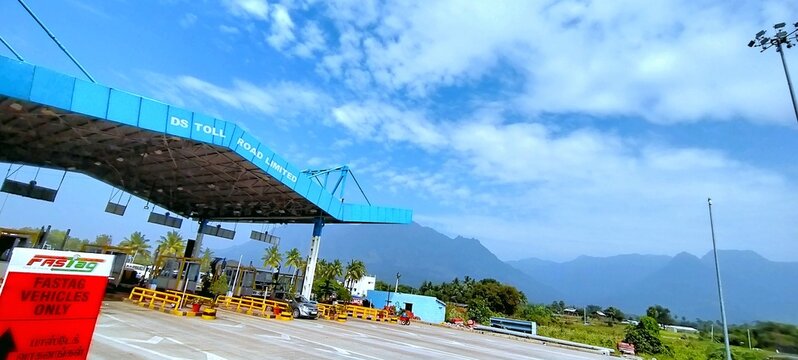 Kodaikanal Road, Tamil Nadu, India - December 27, 2020: Vehicles pass through the DS Toll Road Limited plaza. The toll gate operates with FASTag lanes against the backdrop of scenic hills
