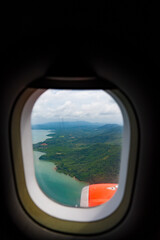 Naklejka premium Aerial view from airplane window showing tropical islands, turquoise sea, and clouds with aircraft engine