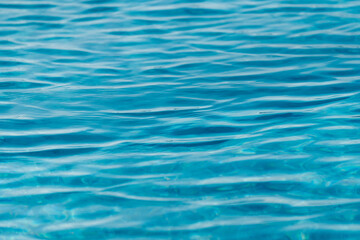 Bright light blue water surface with shimmering wave reflections, abstract liquid texture