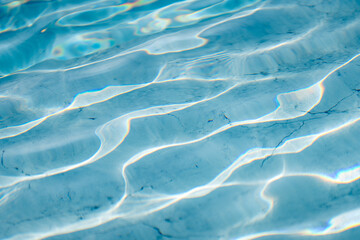 Bright light blue water surface with shimmering wave reflections, abstract liquid texture