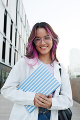 Smiling student holding striped notebook outdoors