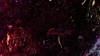 Abstract close-up of wet glass with deep red and purple neon reflections, scattered water droplets, and textured smudges on a dark surface.