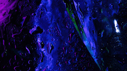 Abstract close-up of wet glass with vivid purple, blue, and green neon reflections, textured with water droplets and smeared light patterns.