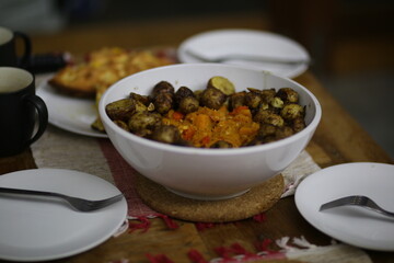 Bowl of young baby potatoes with spices and empty plates beside