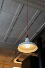 White pendant light fixture hanging from ceiling with warm Edison bulb