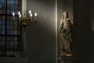 Religious statue illuminated by stained glass light in cathedral setting