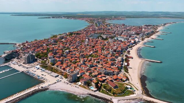 Drone capture Pomorie Bulgaria old town peninsula surrounded Black Sea clear turquoise waters marina boats sandy shores summer travel scene historic architecture vacation landmark popular destination
