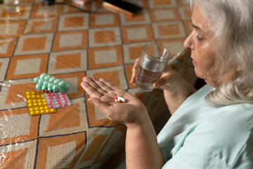 Senior aged woman holding  pills and glass of water. healthcare concept. Elderly woman taking paracetamol, relieves pain from old age osteoarthritis. Muscle pain and fever recovery healthcare concept