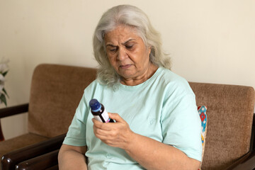 Indian elderly old woman looking cough syrup bottle feeling bad unhealthy expressions while sitting...