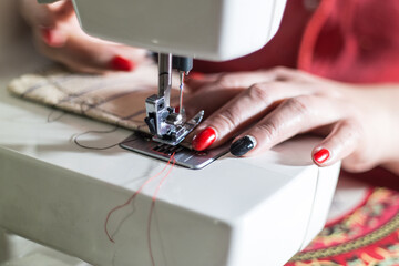 A close-up shot of a person's hands using a sewing machine to work on a piece of fabric, highlighting the craft and attention to detail.