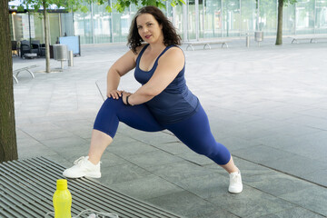 Woman and sports, exercise for weight loss in the fresh air. Happy curvy 40s woman doing workout routine outdoor at city park
