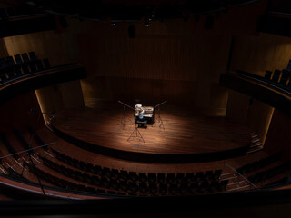 Empty concert hall with grand piano spotlighted on stage awaiting performance