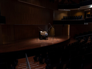 Pianist performing on stage in concert hall with dramatic stage lighting