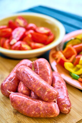 Raw Sausages on Wooden Board and Vegetable Platter
