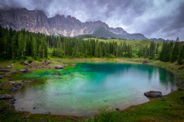 Misty morning at Lago di Carezza in the Dolomites, Italy. Reflections of mountains and forest on the lake surface. Atmospheric alpine landscape.
