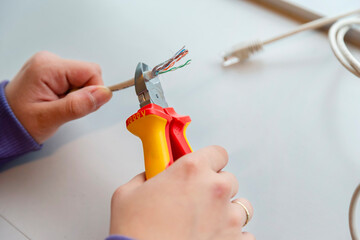 Person using wire strippers to prepare network cable for connector installation during IT setup
