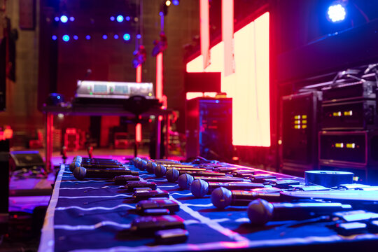 Professional audio mixing board with colorful stage lighting in background during concert production