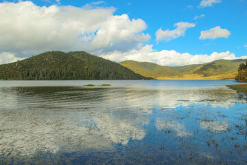 Pudacuo National Park, Yunnan, China, Shangri-La, lake Golden forests surround serene alpine lakes, reflecting clouds.