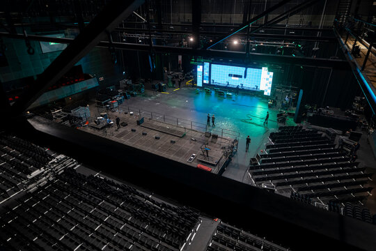 Wide aerial shot of concert arena showing stage crew and technical equipment preparation