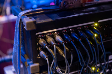 Multiple XLR and audio cables connected to professional sound equipment inputs during concert setup