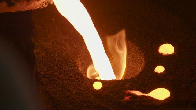 Pouring molten metal into sand casting mold in foundry