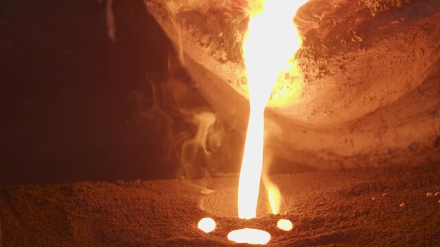 Pouring molten metal into a sand mold creating sparks in a foundry