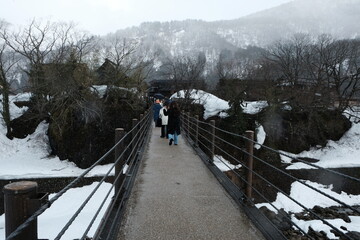People walking on the bridge to the vilage after the snow in Shirakawa Village, Gifu, Japan