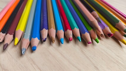 Education and creativity concept with color pencils on wooden background. Close-up photo with soft natural light and horizontal composition.