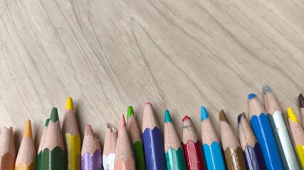 Top-down view of colored pencils over textured wood. Bright tones on rustic surface symbolizing creativity, back to school, and artistic inspiration.