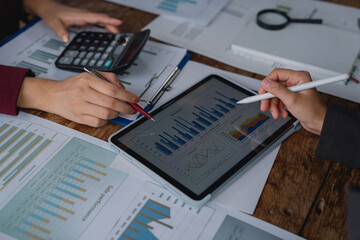 Business team analyzing financial charts and graphs on digital tablet during a meeting to plan marketing strategy and business investment planning
