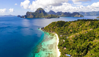 Aerial photography over the sea coast with towering limestone cliffs, stunning turquoise-blue lagoons, and pristine white sandy beaches