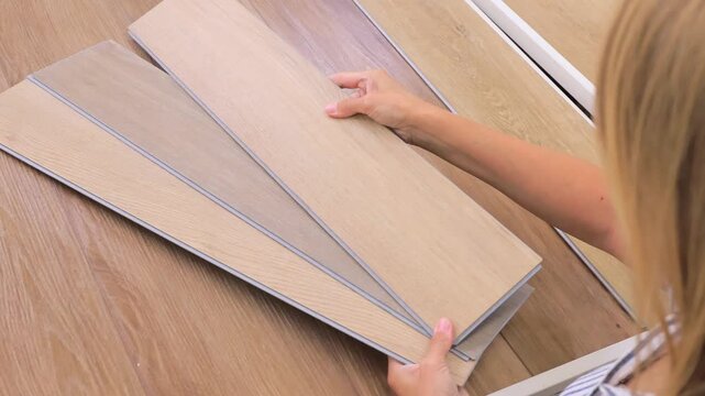Woman choosing wooden laminate flooring panels in hardware and home improvement store