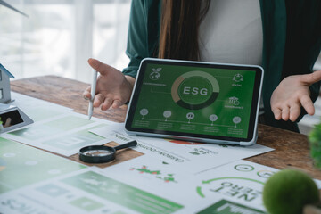 Businesswoman is using a tablet showing ESG environmental social and governance data, analyzing...